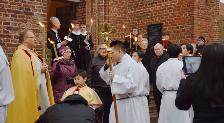 Folk med fakler foran kirke